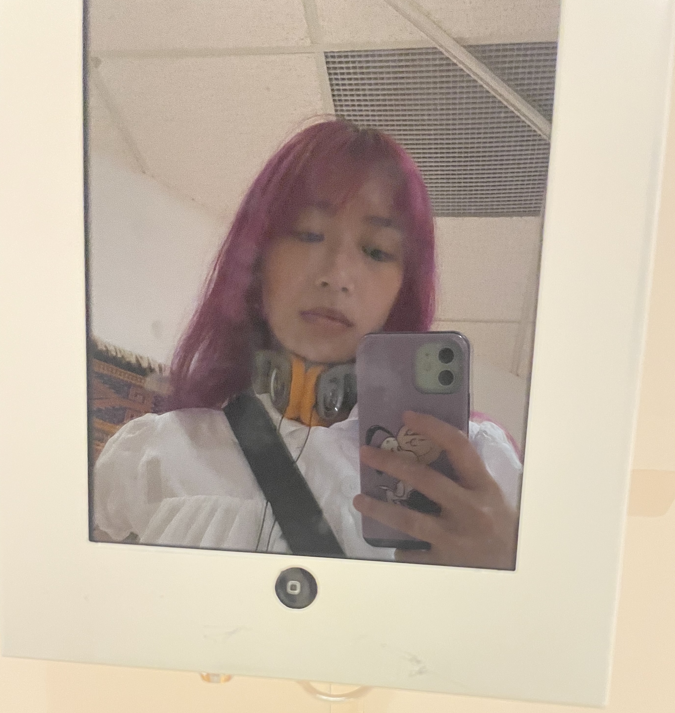 chinese-canadian woman with magenta hair taking a selfie in the dark screen of an iPad that didn't work at a museum