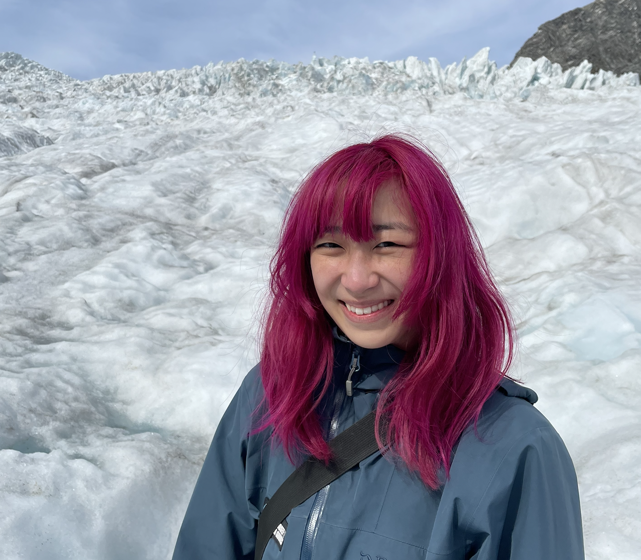 chinese-canadian woman with magenta hair on a snowy glacier smiling at the camera